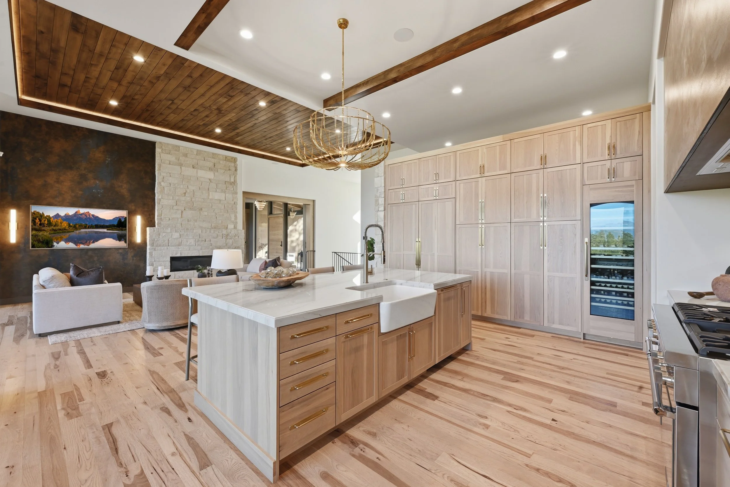 Open-concept kitchen and living room with wooden flooring, cabinetry, a kitchen island, and a wall-mounted TV.