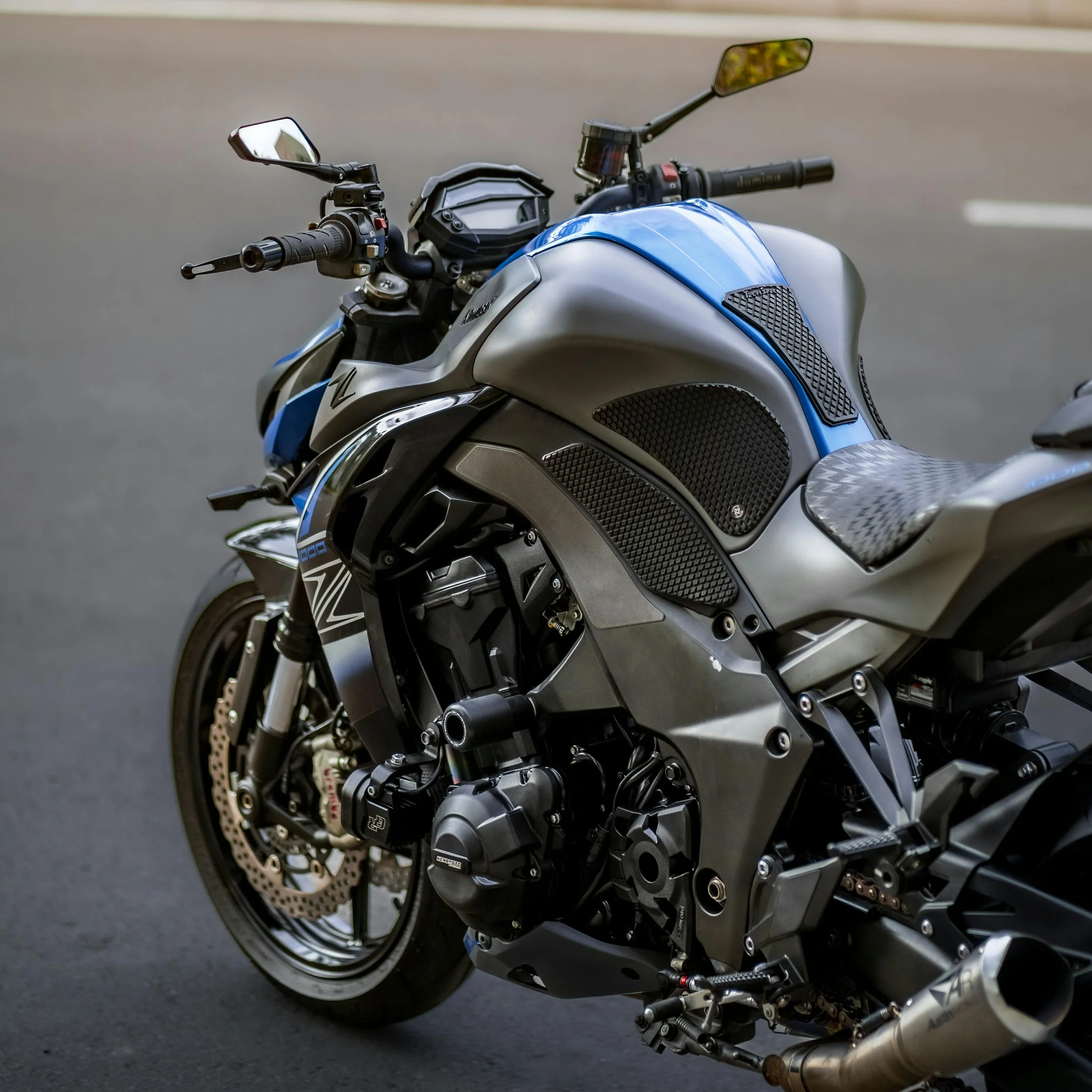 Close-up view of a modern motorcycle with detailed engine and handlebar components, parked on asphalt.