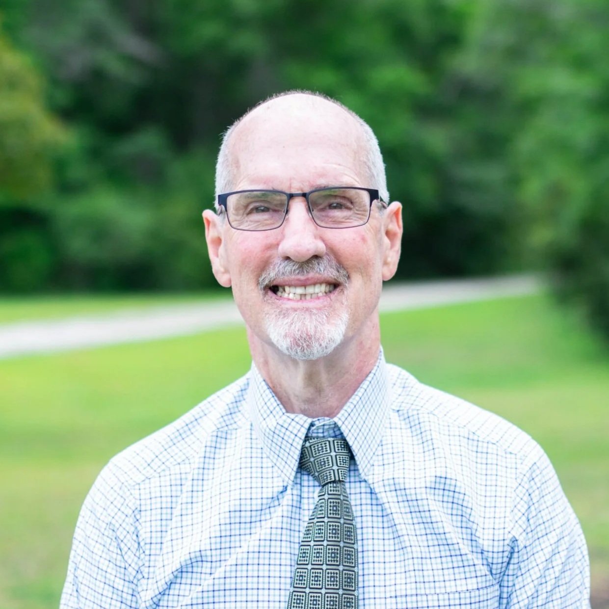 Michael Hardin the owner of Hardin Insurance wearing a checkered shirt and a patterned tie, standing outdoors at his home in Callahan Florida