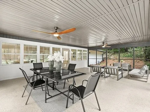Enclosed patio with dining table, chairs, and outdoor seating area with sofas and chairs.