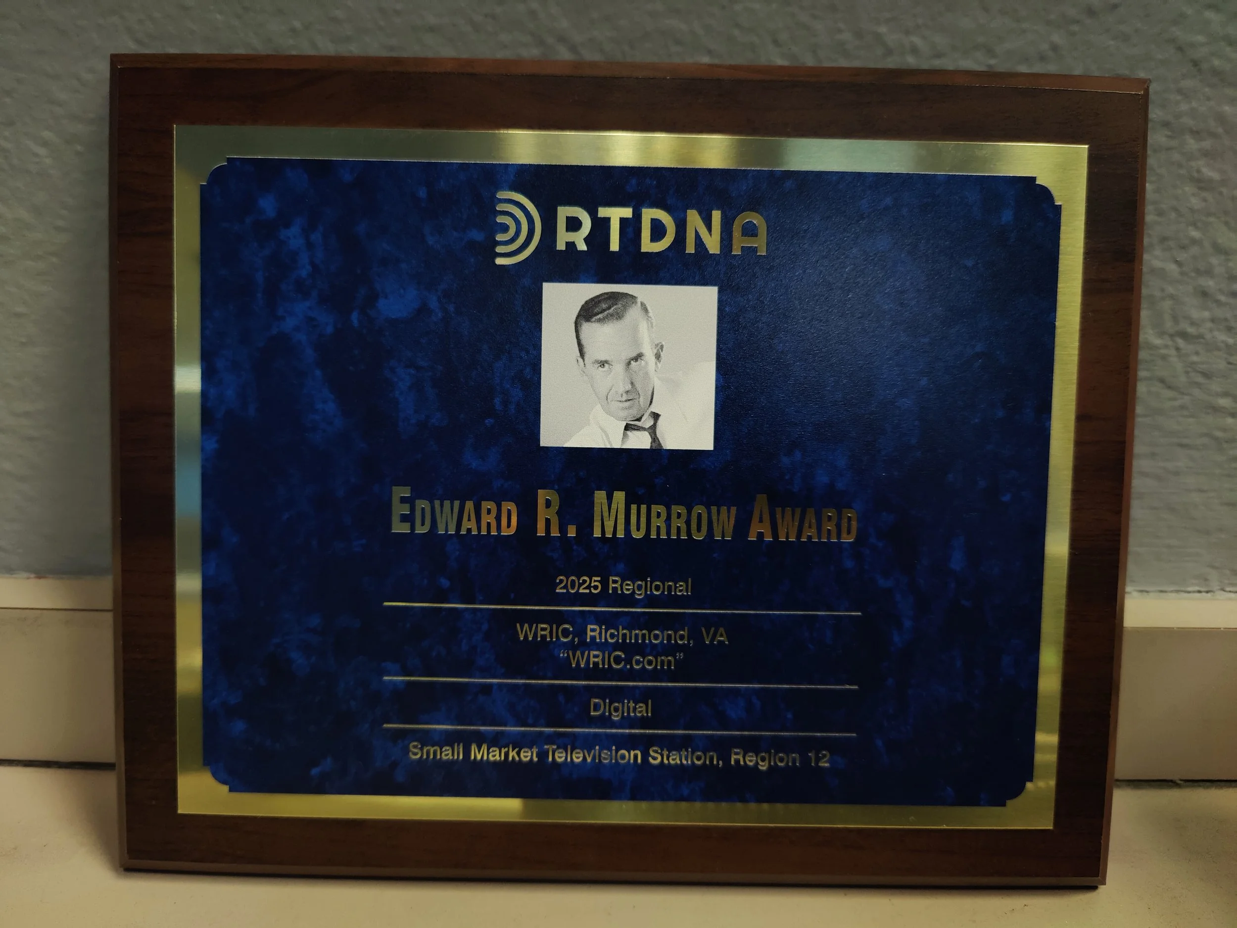 Plaque with a black and white photo of a man in a suit, text referencing the Edward R. Murrow Award, and details about the award ceremony and location.