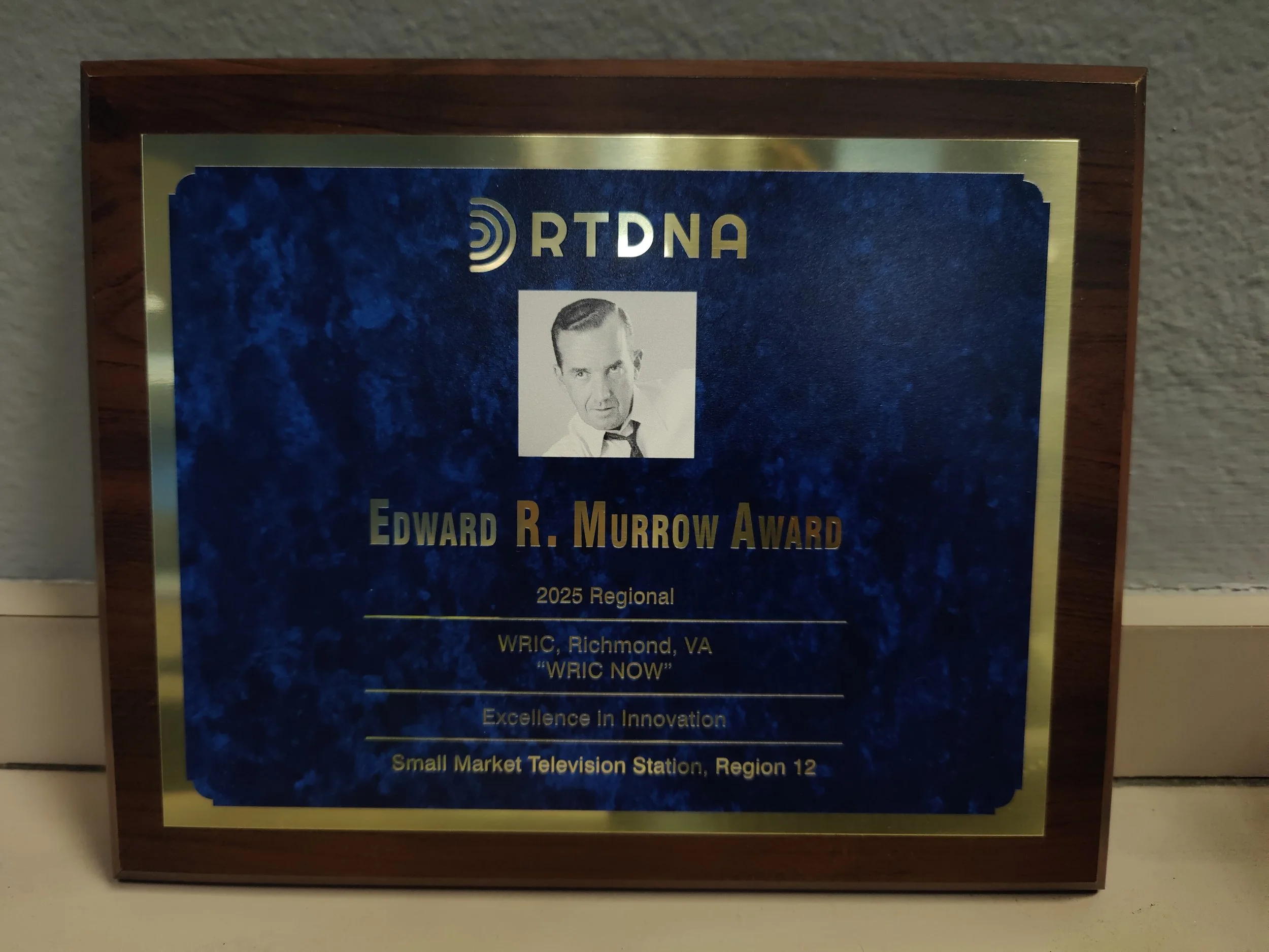A plaque with a photograph of a man and text including 'Edward R. Murrow Award,' and details about a regional award from 2025 given to WRIC in Richmond, VA.