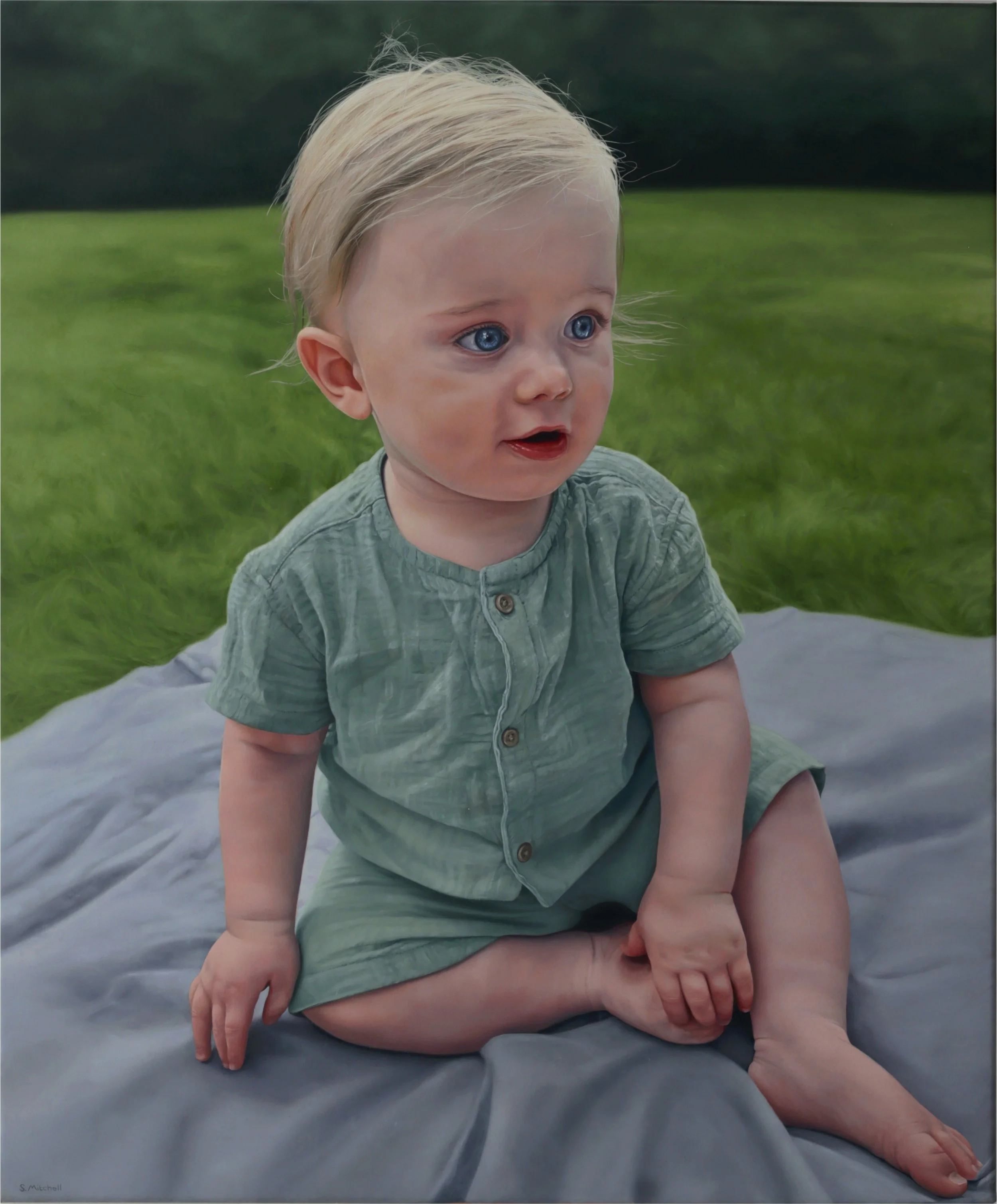 A young child with blond hair and blue eyes sitting on a bed outdoors on a cloudy day, with grass in the background, wearing a green shirt with buttons.