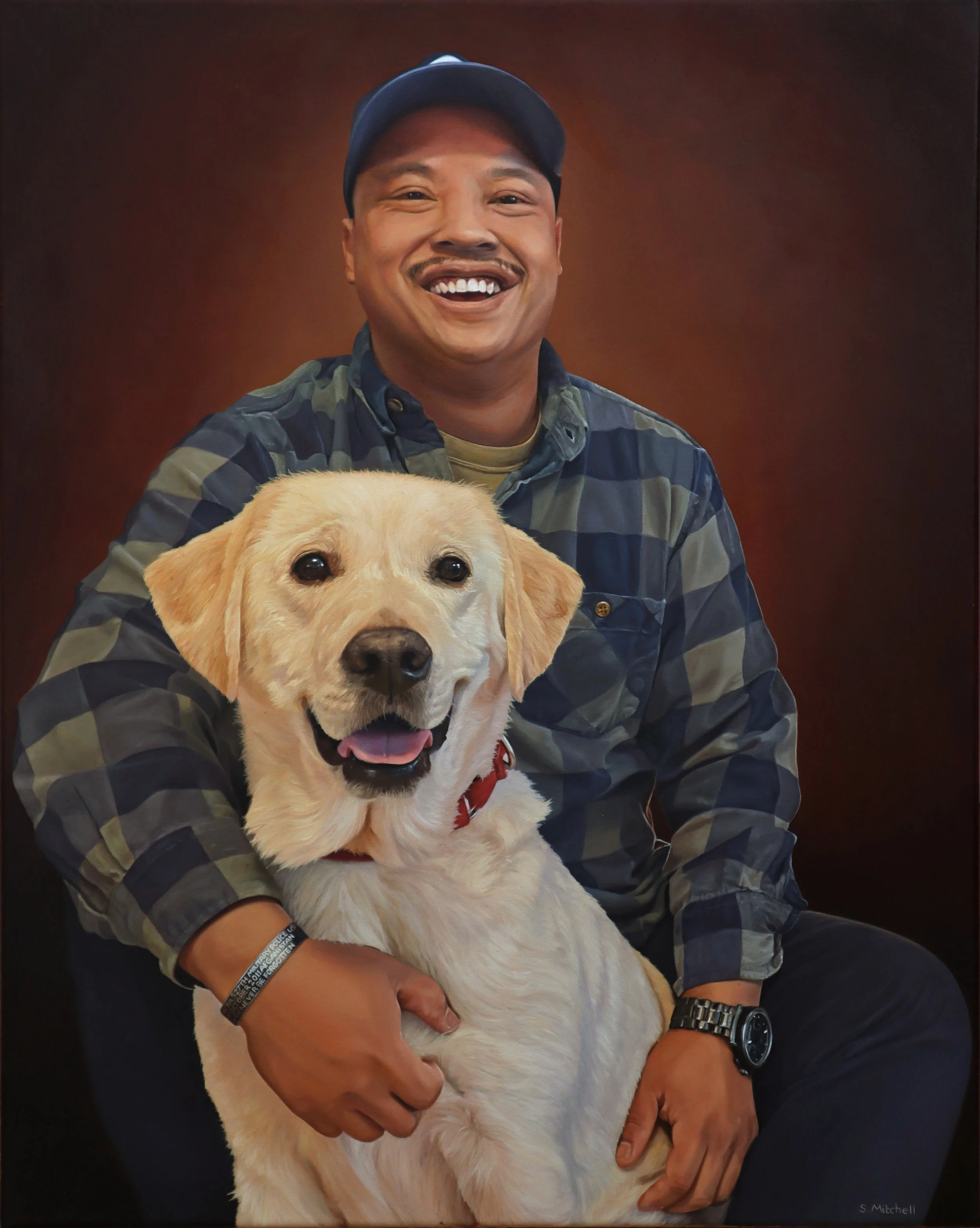 A smiling man wearing a dark baseball cap and camouflage jacket is holding a Labrador retriever puppy with light yellow fur. The puppy has its tongue slightly out and looks directly at the camera. The background is a plain, warm brown color.