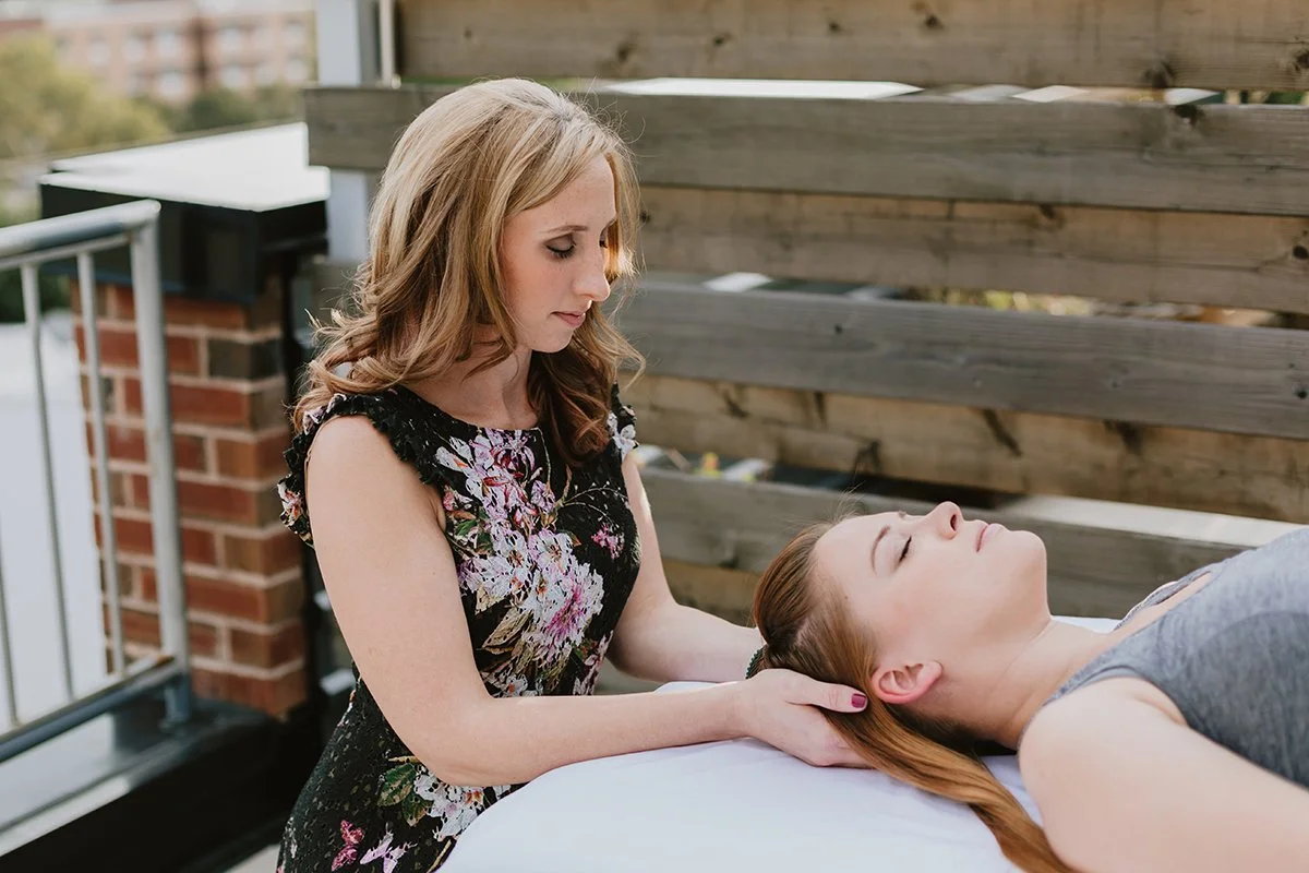 A woman receiving a massage on her neck outdoors on a balcony.