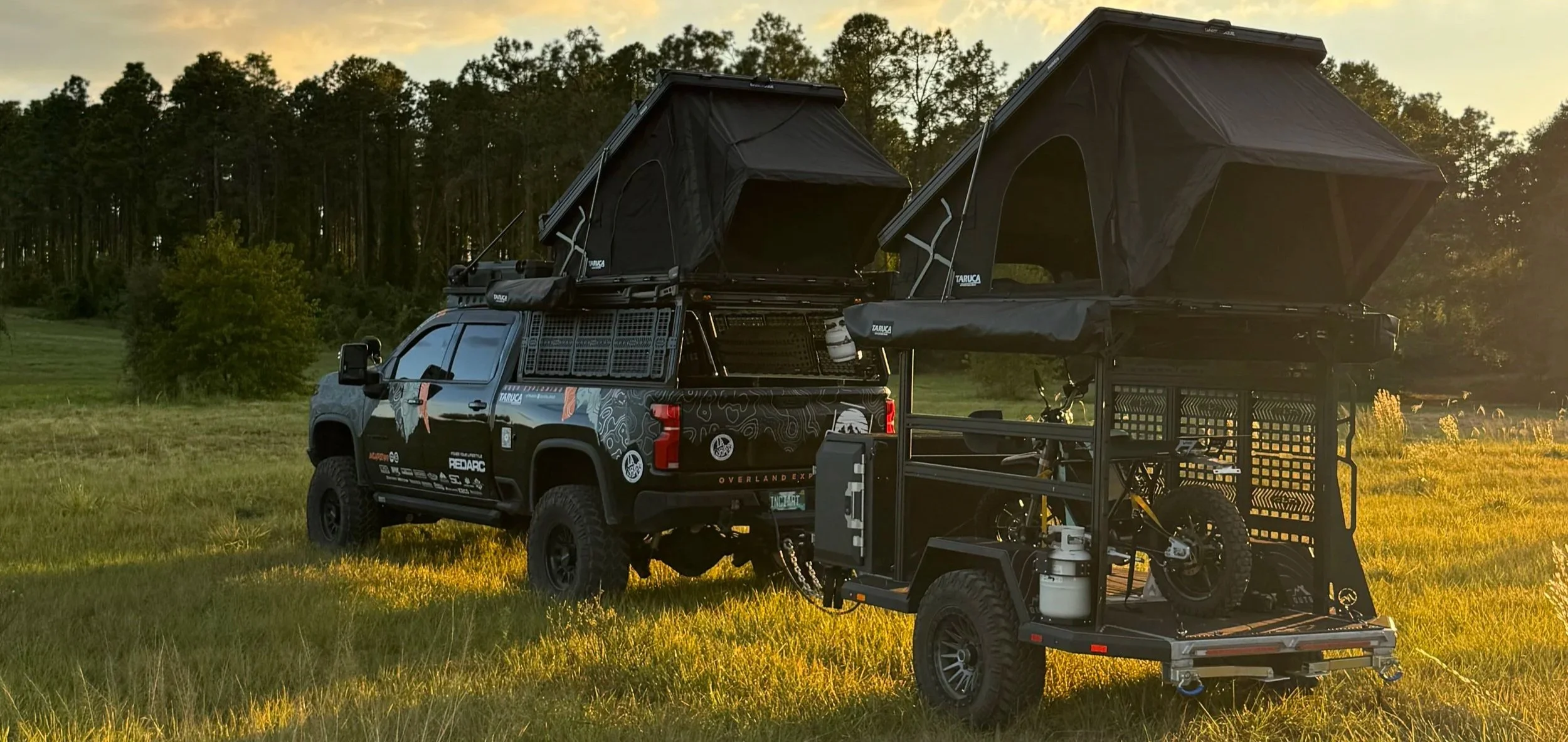 INCIARTE4X4 Chevrolet Silverado 2500 and overland trailer camp setup with rooftop tents during a sunset camping adventure.