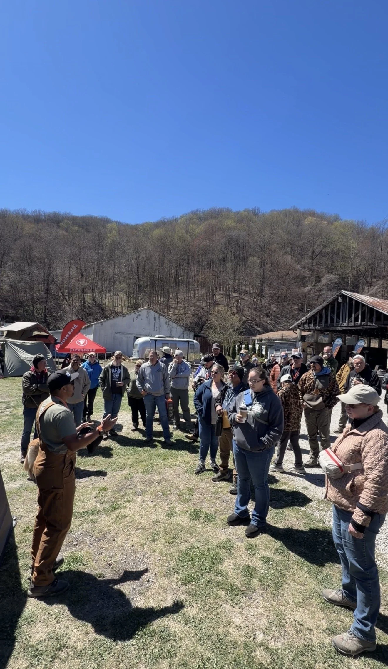 Overland community gathering with camping rigs and outdoor gear during an overland event.