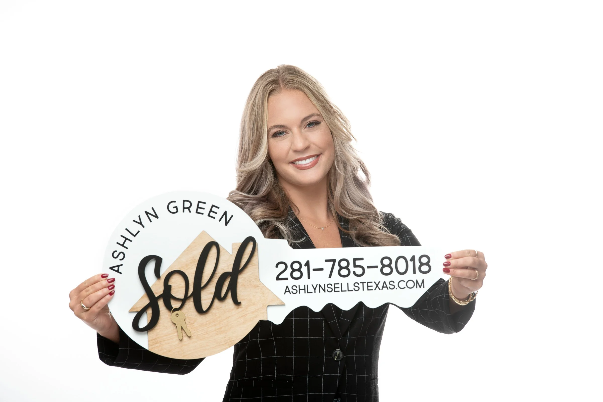 A woman with blonde hair smiling, holding signs that says 'Sold' and includes contact information, against a plain white background.