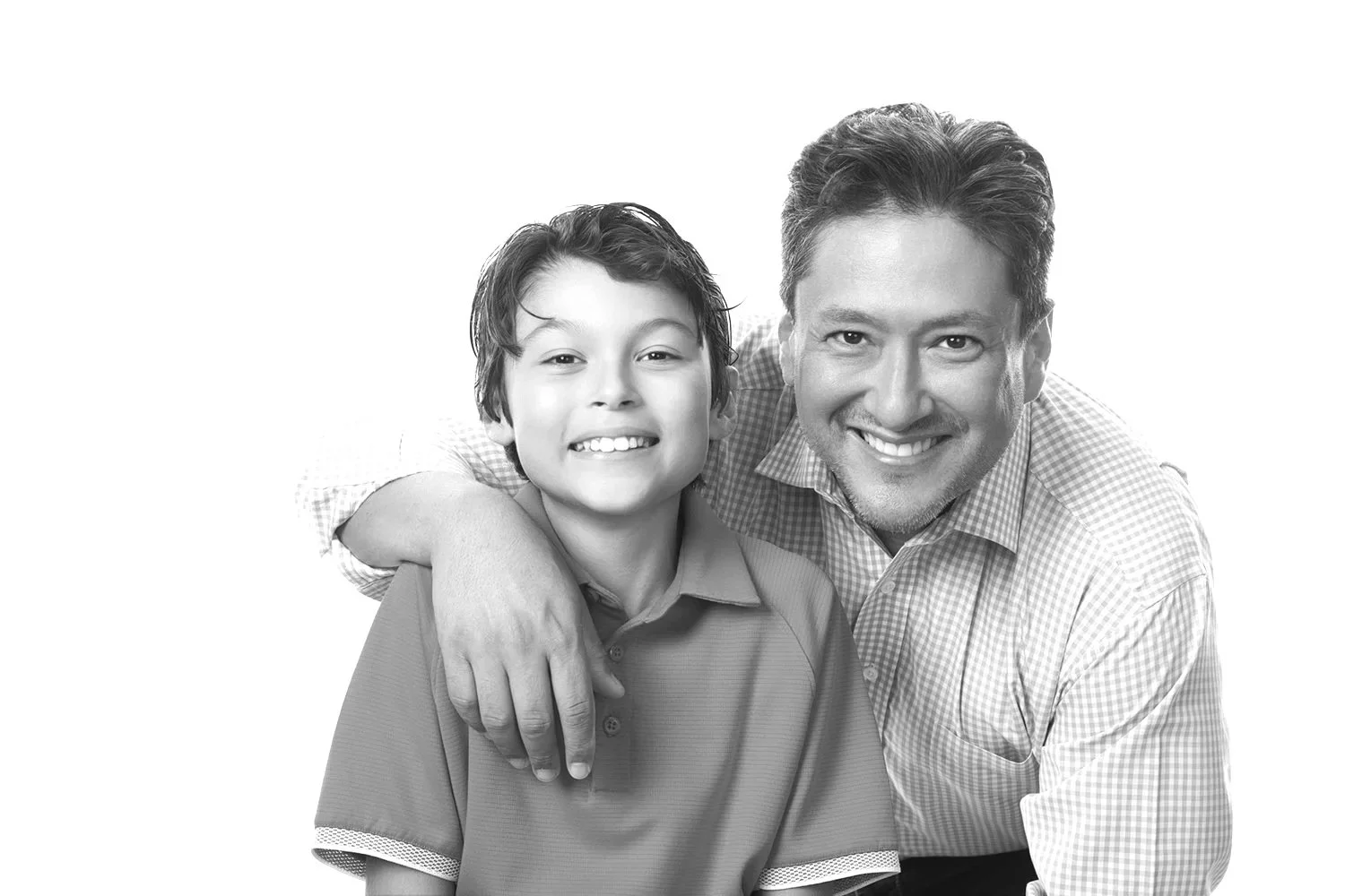 A black and white photo of a smiling man with dark hair embracing a young boy with dark hair, both looking at the camera.
