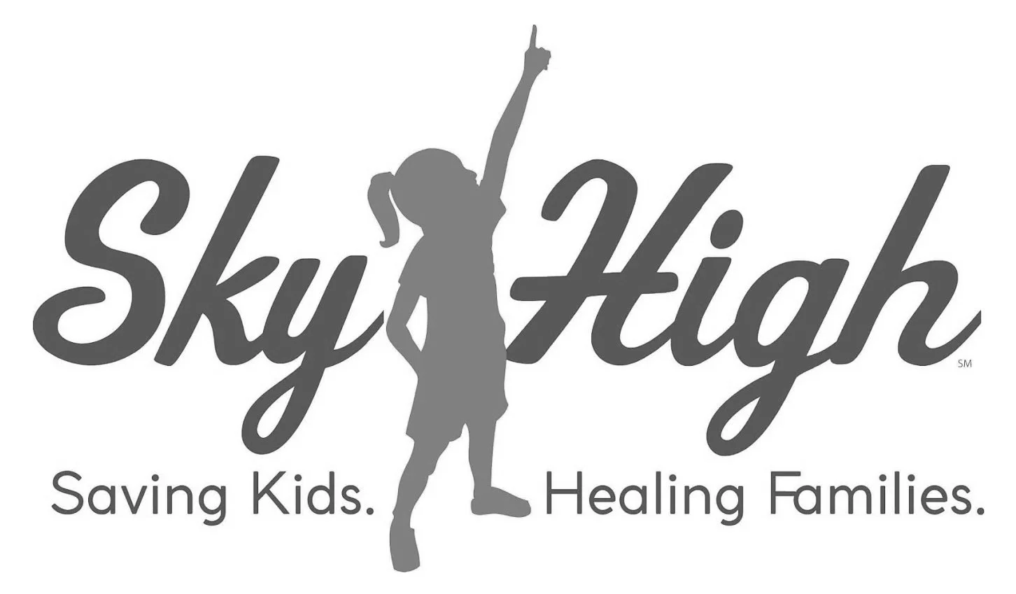 Logo for Sky High, featuring a silhouette of a girl in a basketball uniform jumping to dunk a basketball with her arm extended. The words "Sky High" are written in large cursive letters, with the tagline "Saving Kids. Healing Families." underneath.