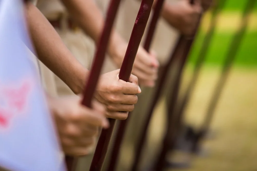 Close-up of multiple people's hands gripping red metal bars in a row