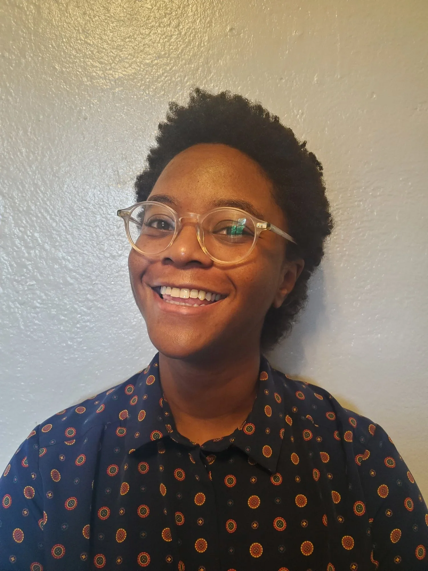 Cassandra Mensah founding attorney, a Black woman smiling, with clear glasses wearing a navy shirt with patterns