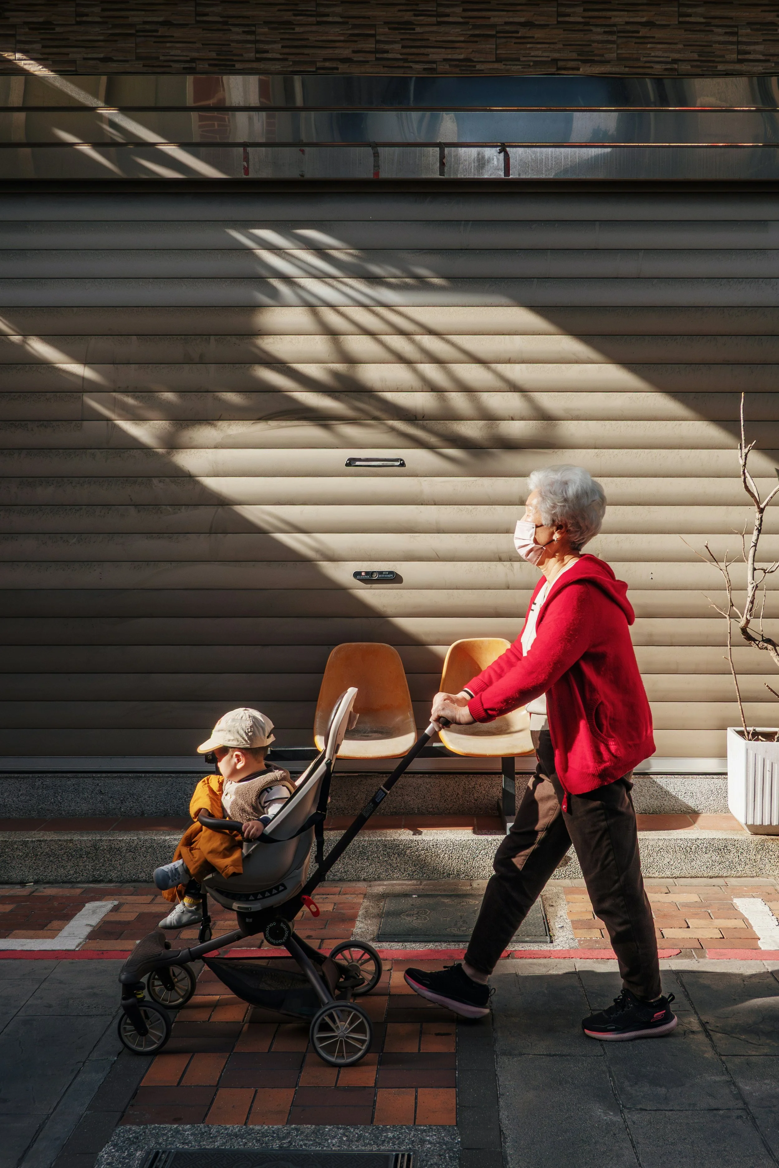 Elderly person walking with child in stroller