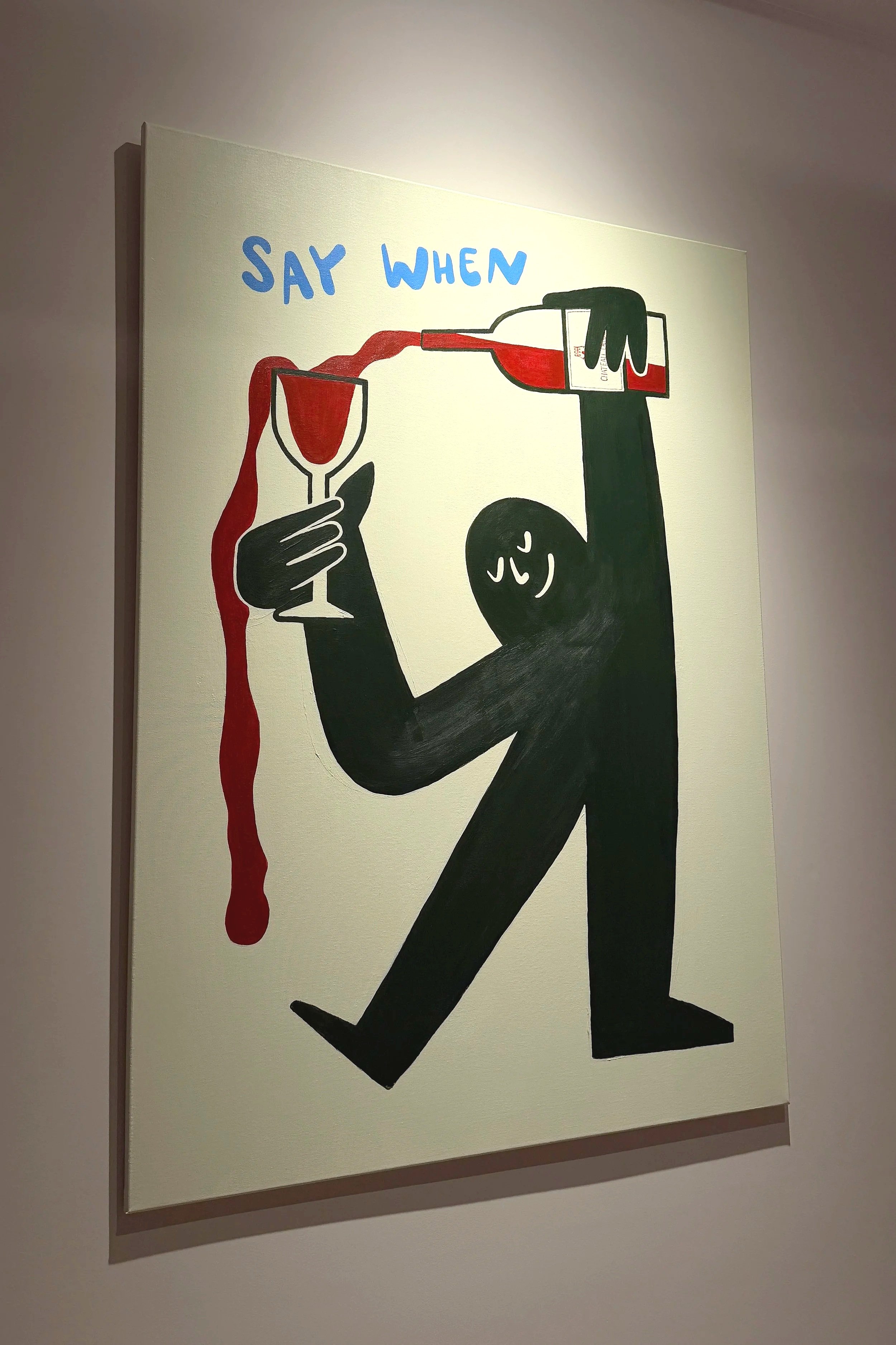 Artwork of a black stylized figure with a smiling face, holding a wine glass with red wine in one hand, and pouring red wine from a bottle into the glass with the other hand. The phrase "SAY WHEN" is written in blue at the top of the artwork.