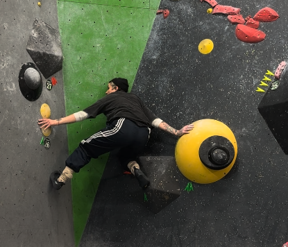 Person climbing an indoor rock climbing wall with colorful holds.