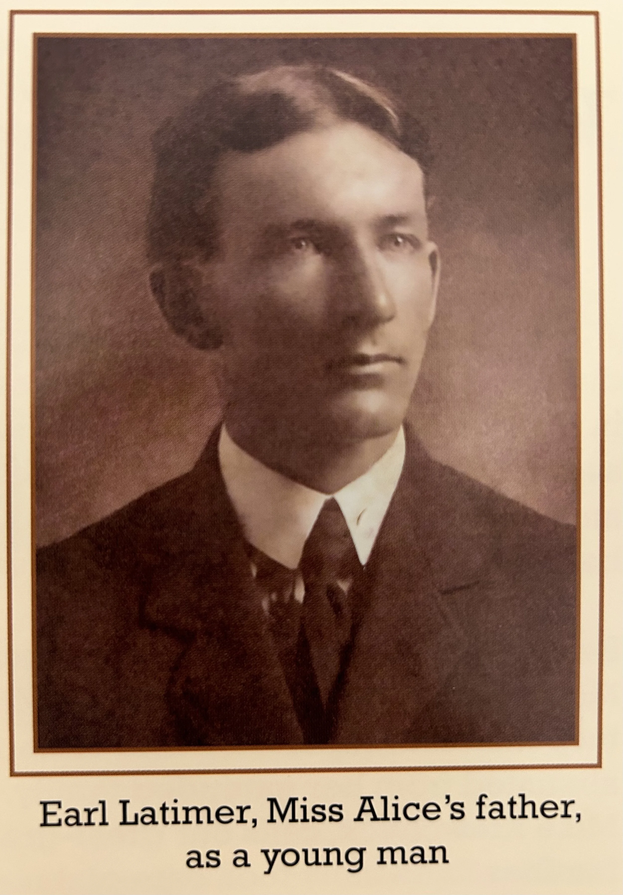 Black and white portrait of Earl Latimer as a young man, wearing a suit and tie, taken from a historical photograph