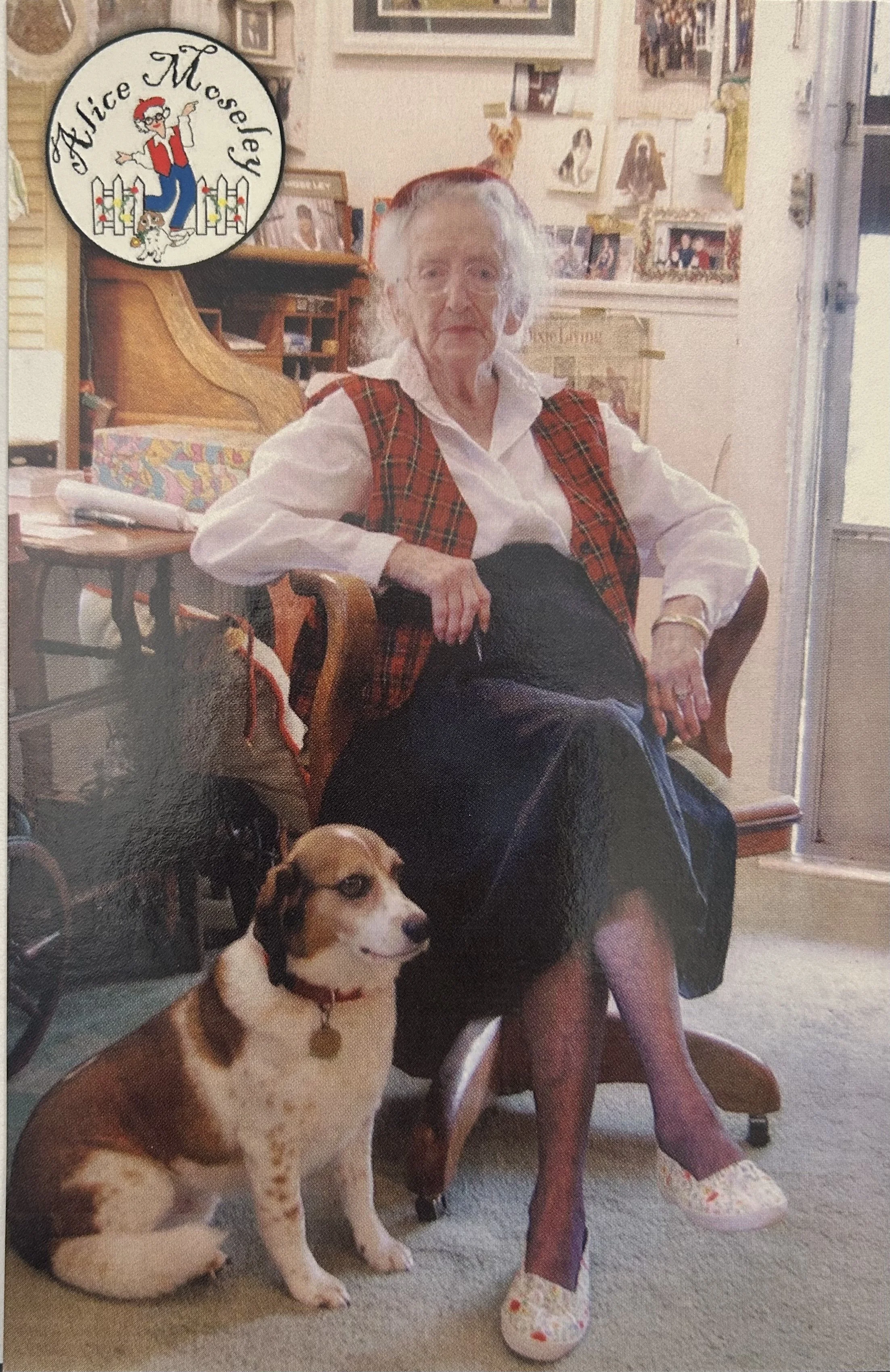 An elderly woman with gray hair sitting in a wooden armchair with a dog at her feet. The woman is wearing a red plaid vest, white shirt, and floral slippers. The background shows framed photos and a small bookshelf. There is a dog-themed logo in the top left corner reading 'Alice Mosley' with a cartoon woman, a dog, and a white picket fence.