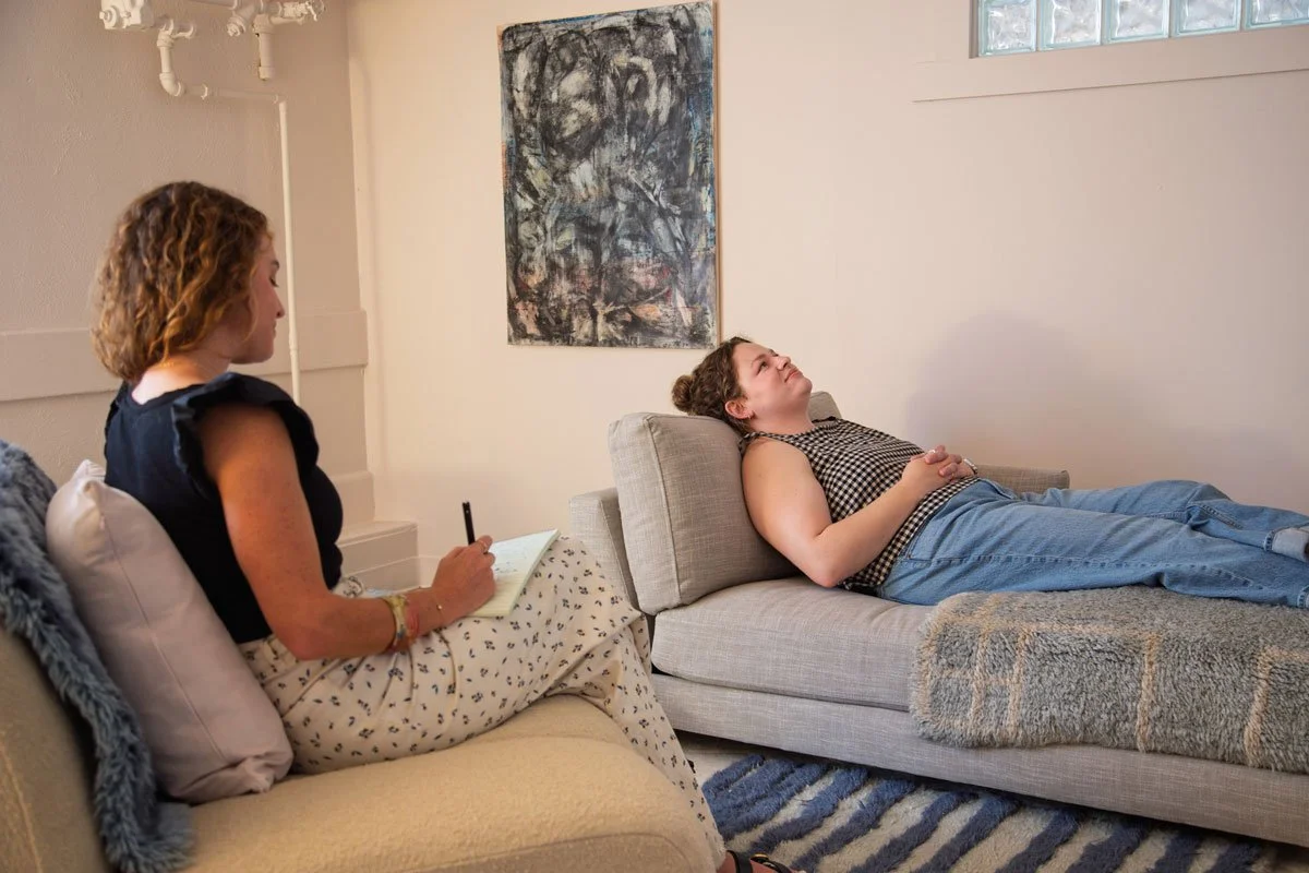 A woman lying on a couch and talking to a therapist in a therapy session in East Falls, Philadelphia.