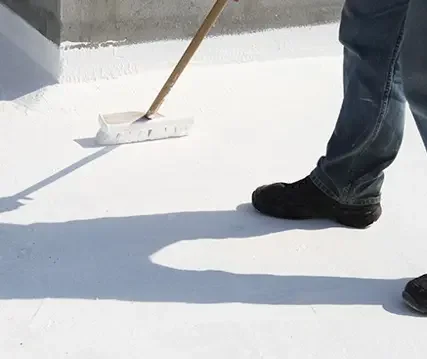 Person standing on a white surface, holding a broom, with their shadow visible.