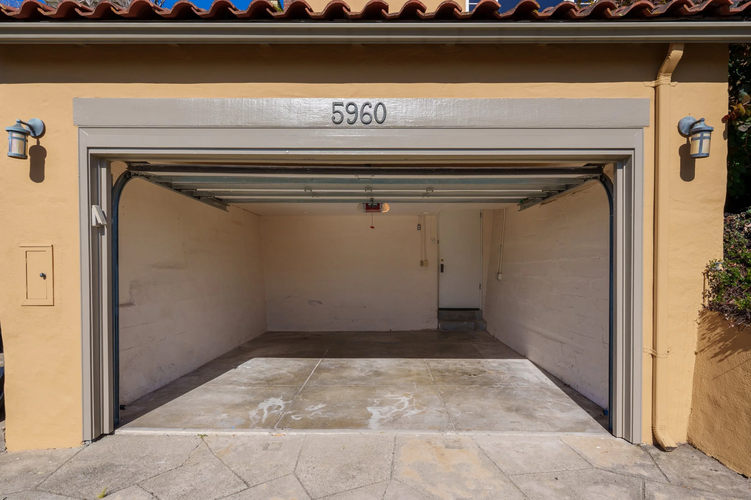 Empty garage with beige walls and a concrete floor, with house number 5960 displayed above the garage opening.