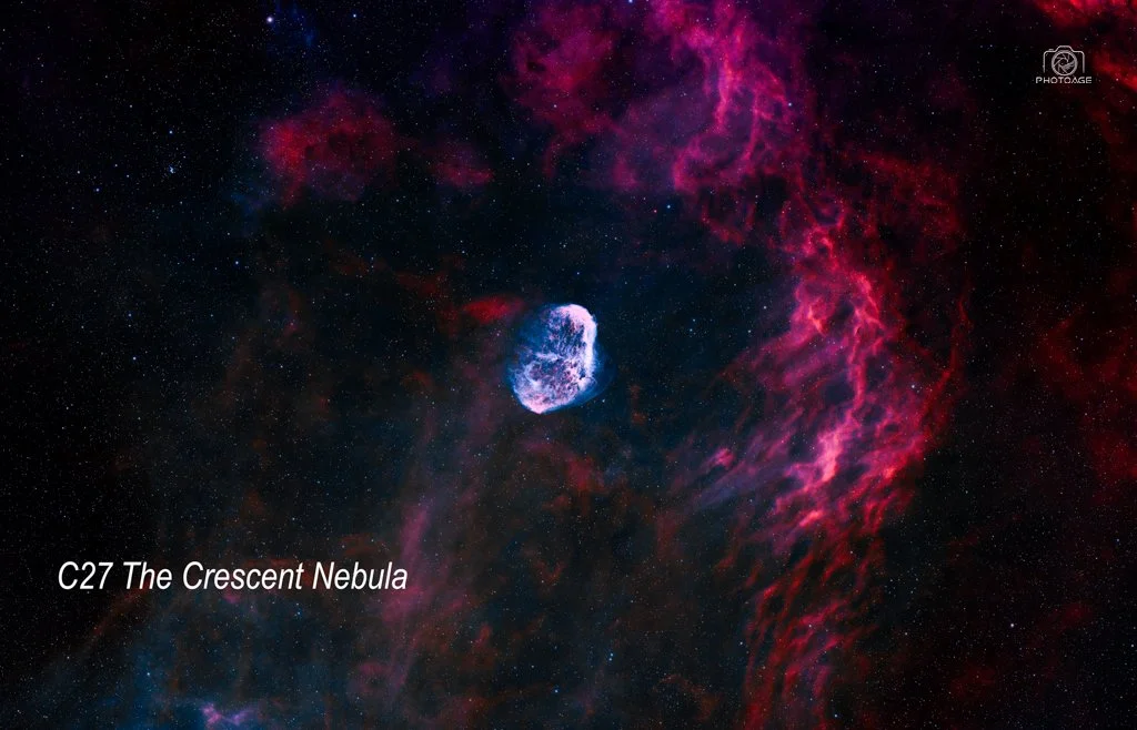 A space scene showing a nebula with pink and purple hues, a small glowing celestial object in the center, and stars scattered across the background. Text in the lower left corner reads 'C27 The Crescent Nebula'.