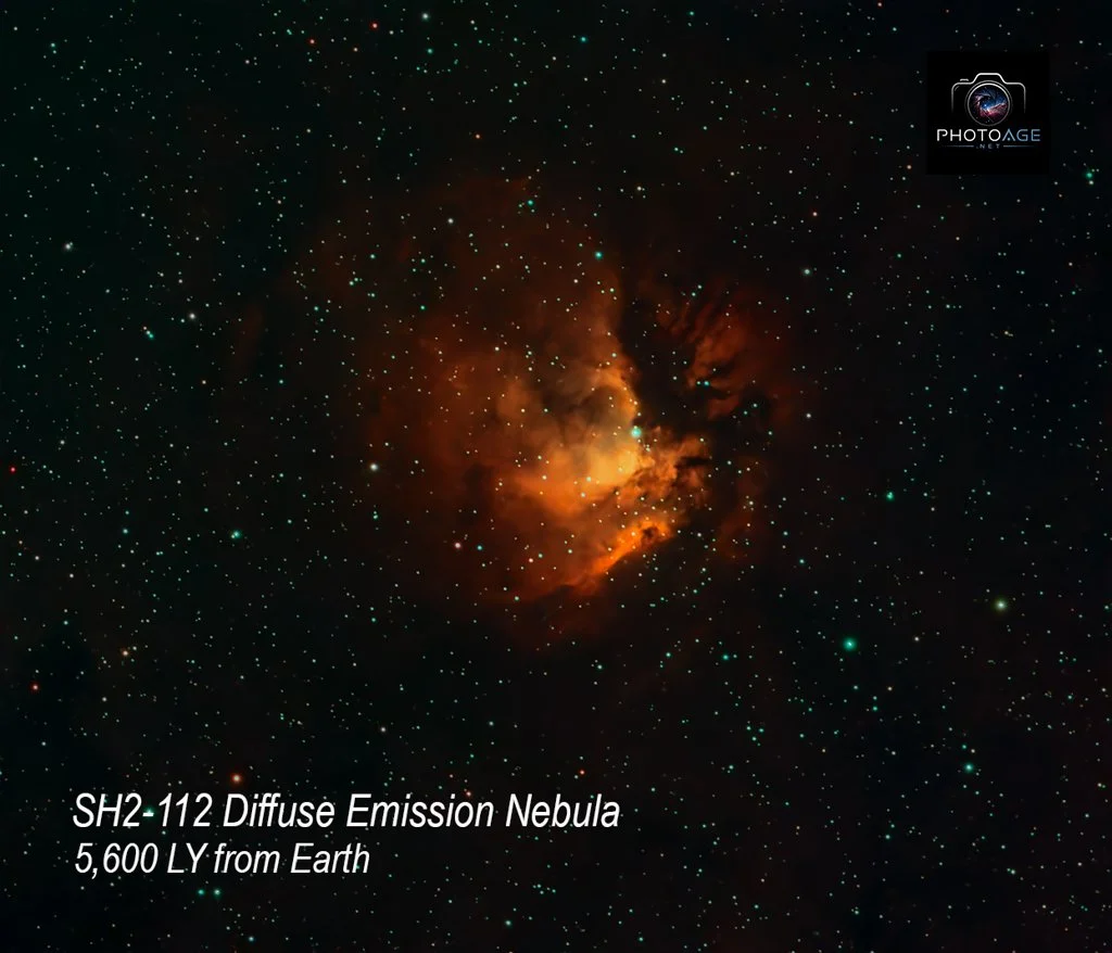 A detailed photo of the SH2-112 diffuse emission nebula in space, showing a bright, orange cloud of gas and dust surrounded by numerous stars at a distance of 5,600 light-years from Earth.