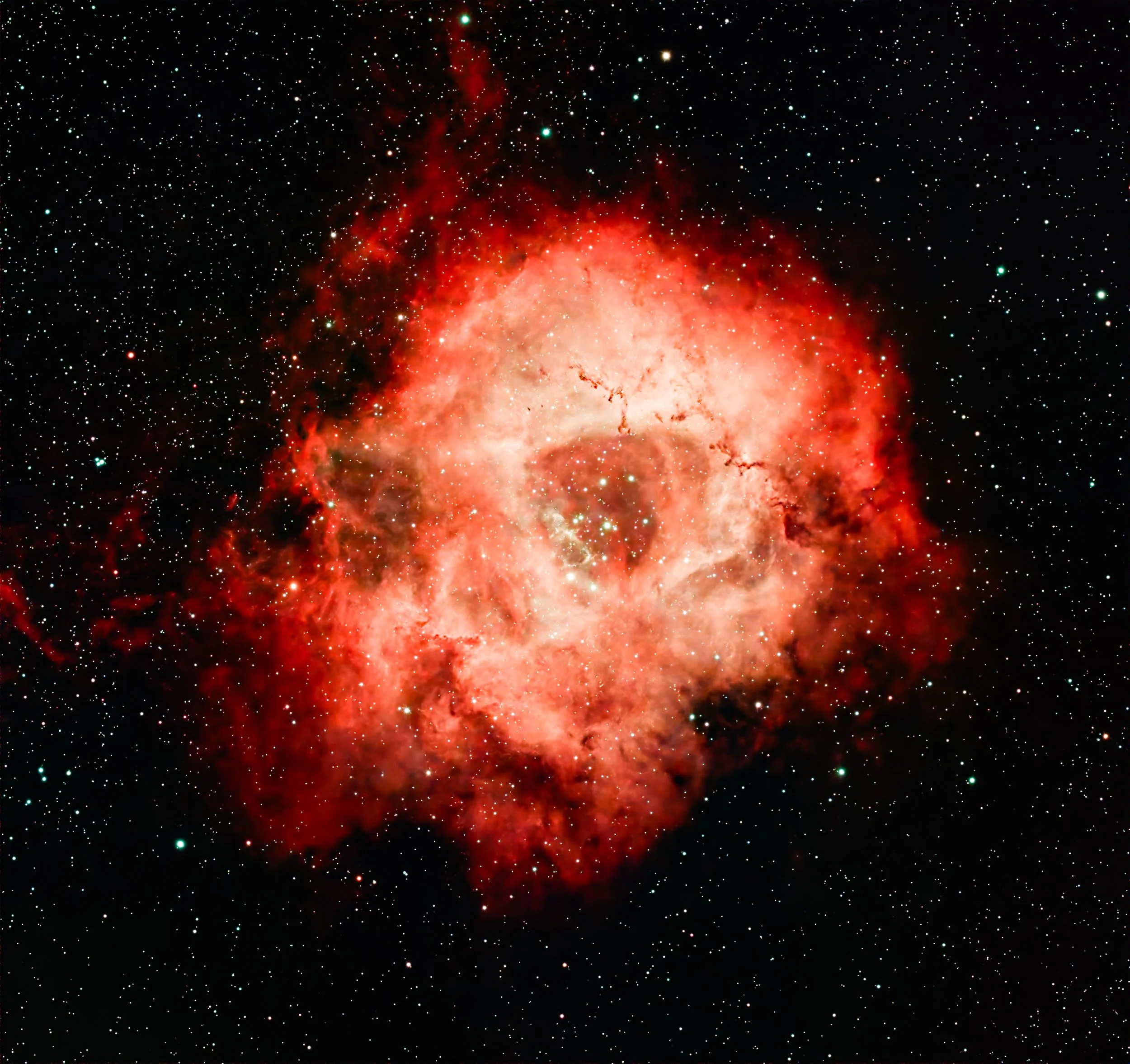 A vibrant image of a nebula in space with bright red and orange colors, surrounded by numerous tiny white stars.
