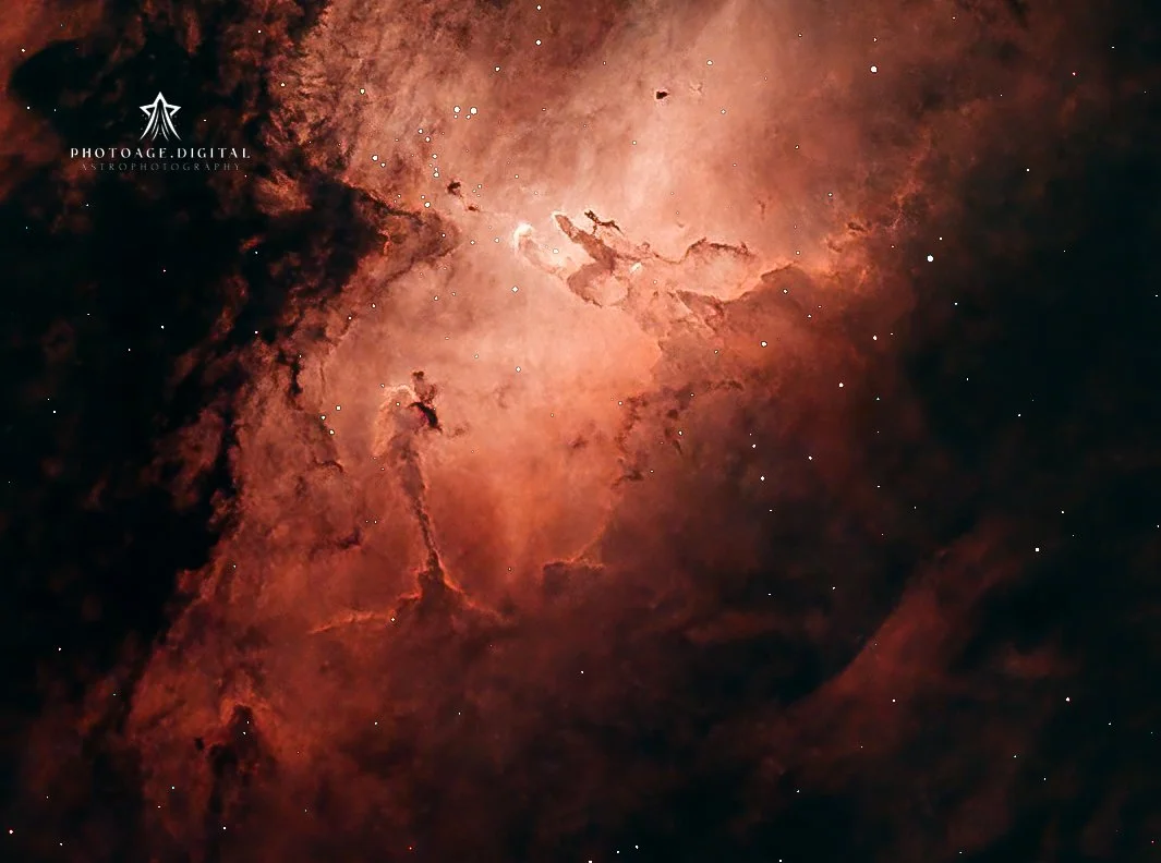 A detailed image of a red and orange nebula in space with stars scattered throughout.