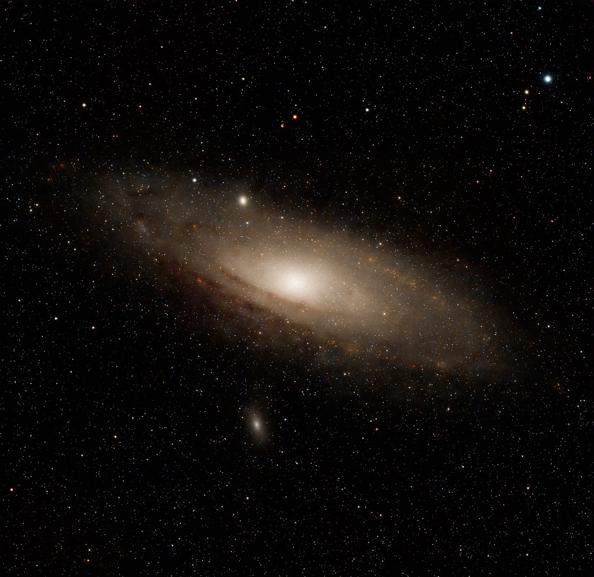 A vast view of outer space with numerous stars and a bright galaxy or nebula towards the bottom of the image.
