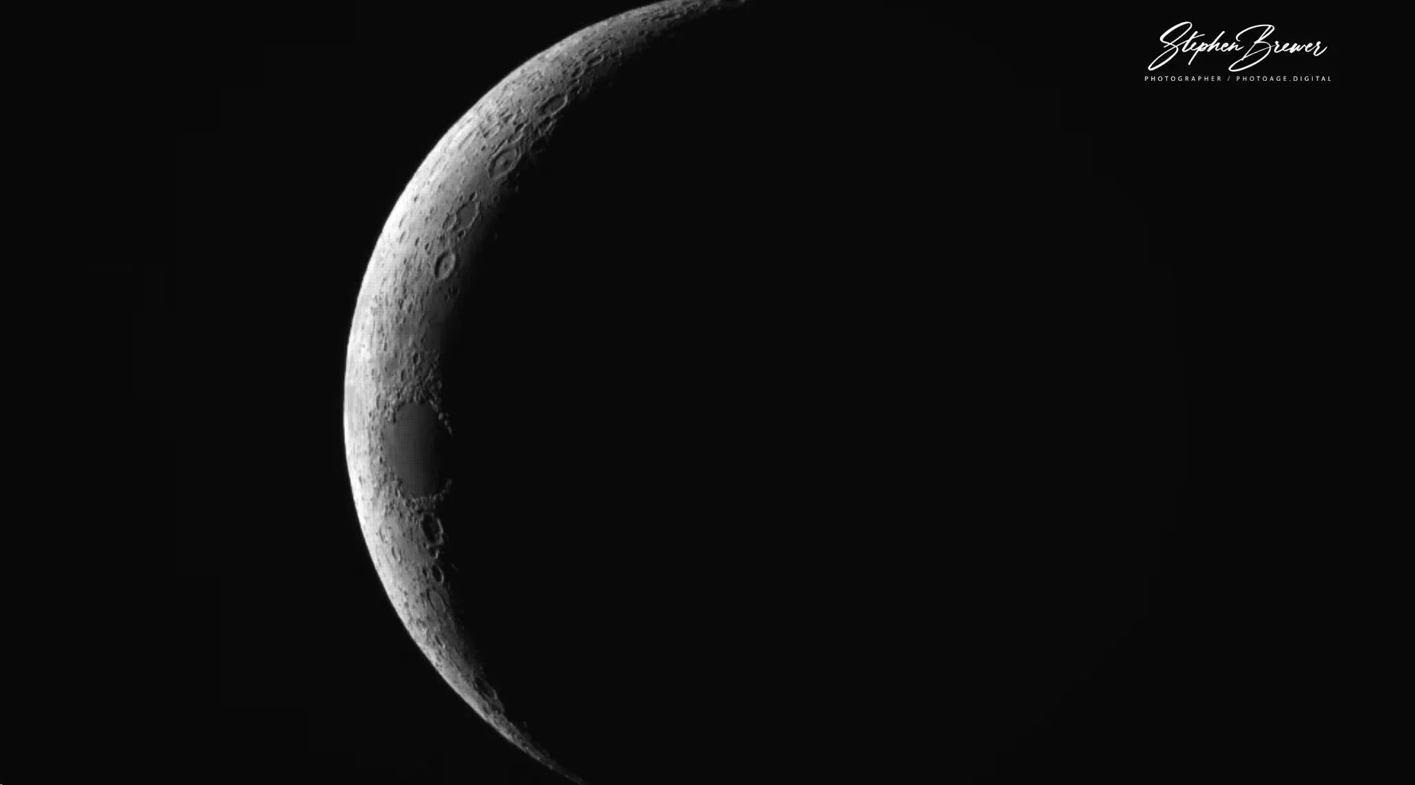 A detailed black and white photograph of the Moon's crescent phase, showing craters and surface textures, with a black background.