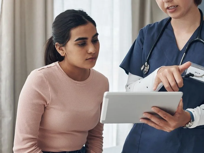 A patient reviewing information on a tablet with a clinician