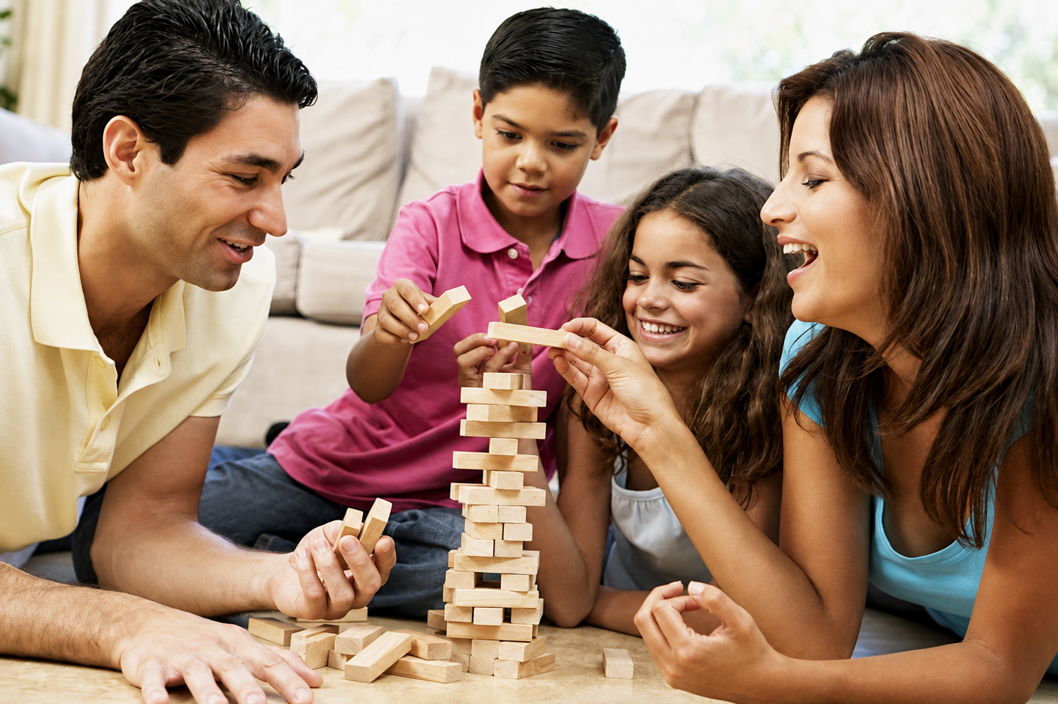 Family playing Jenga game on the floor of a living room.
