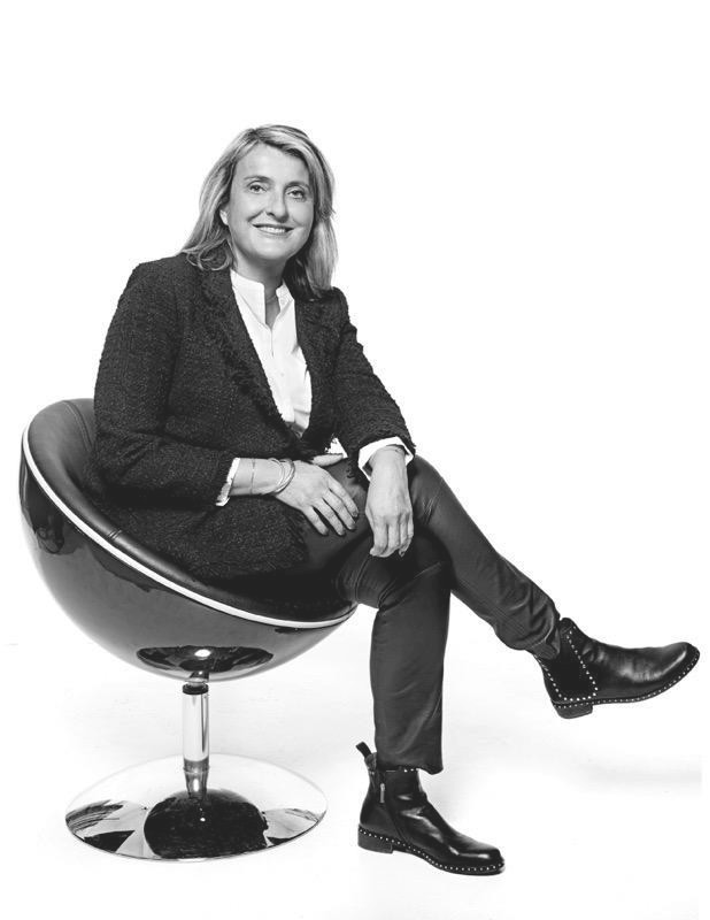 Femme assise sur un fauteuil sphérique, souriante, en noir et blanc.