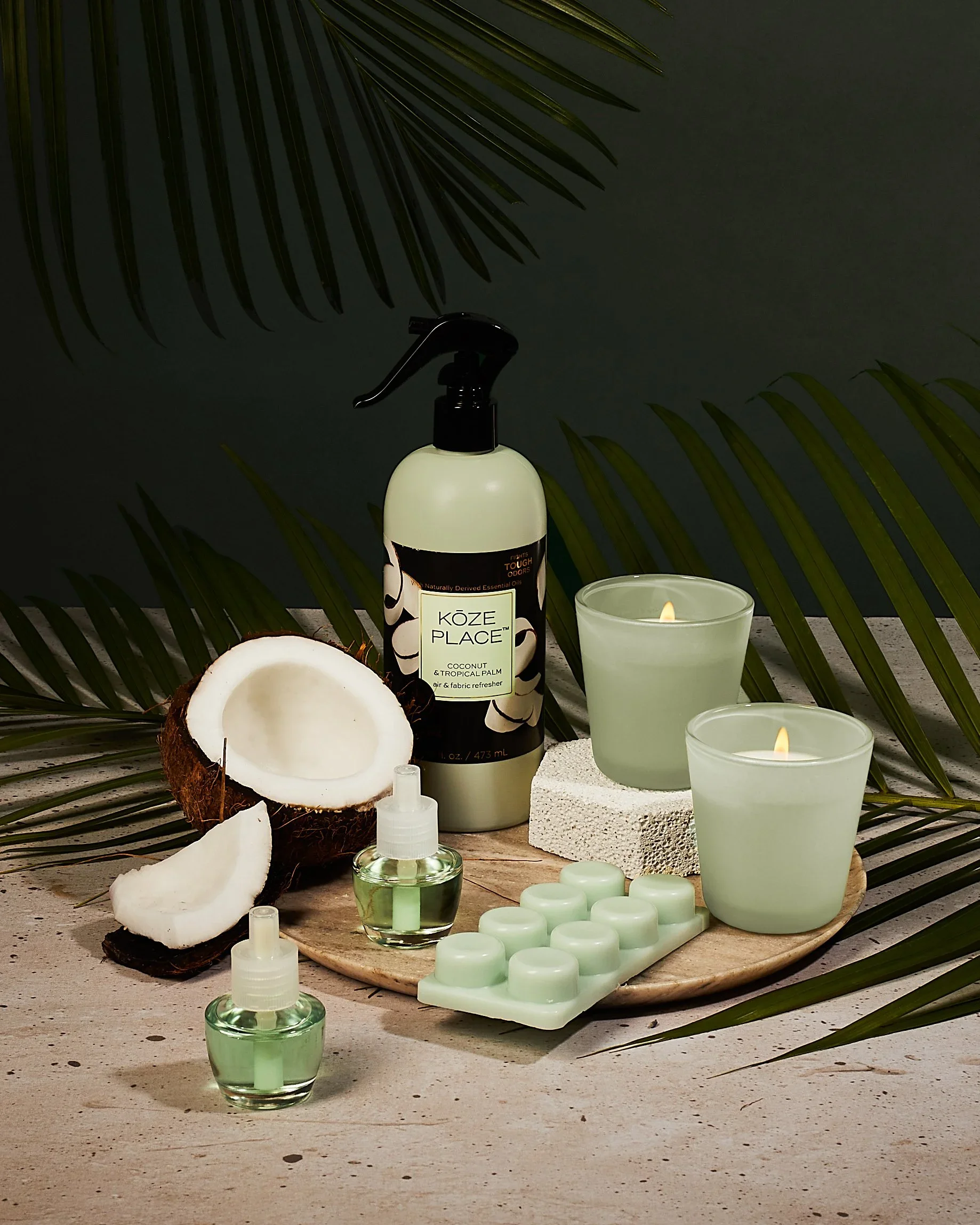 A spa or wellness setting with coconut, candles, and skincare products on a wooden tray, surrounded by palm leaves and dark background.