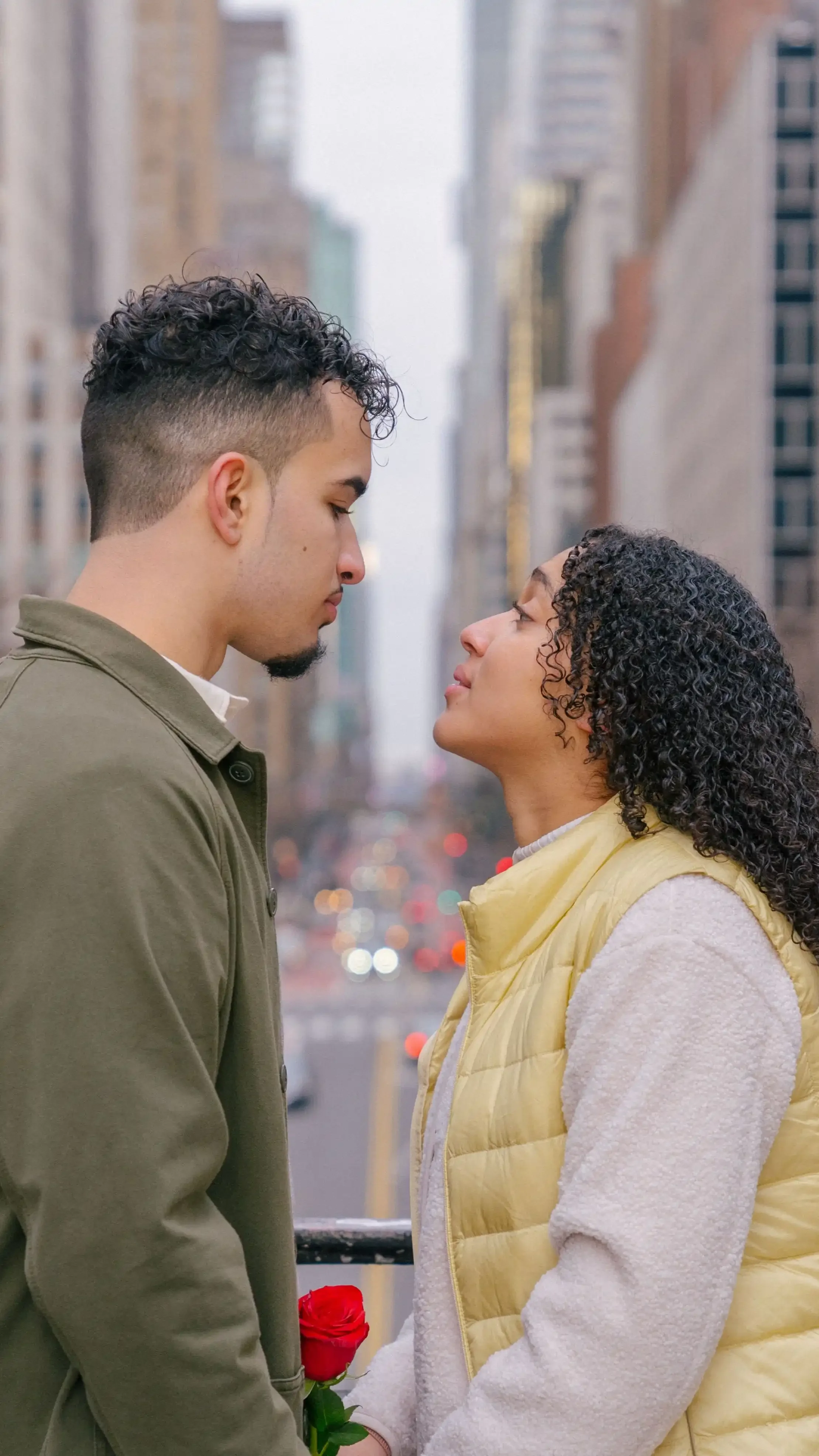 Young hispanic couple closely facing each other with rose