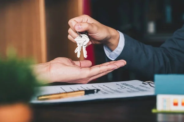 Close up two people handing over a set of house keys