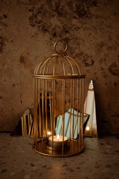 Gold small bird cage with a candle in it