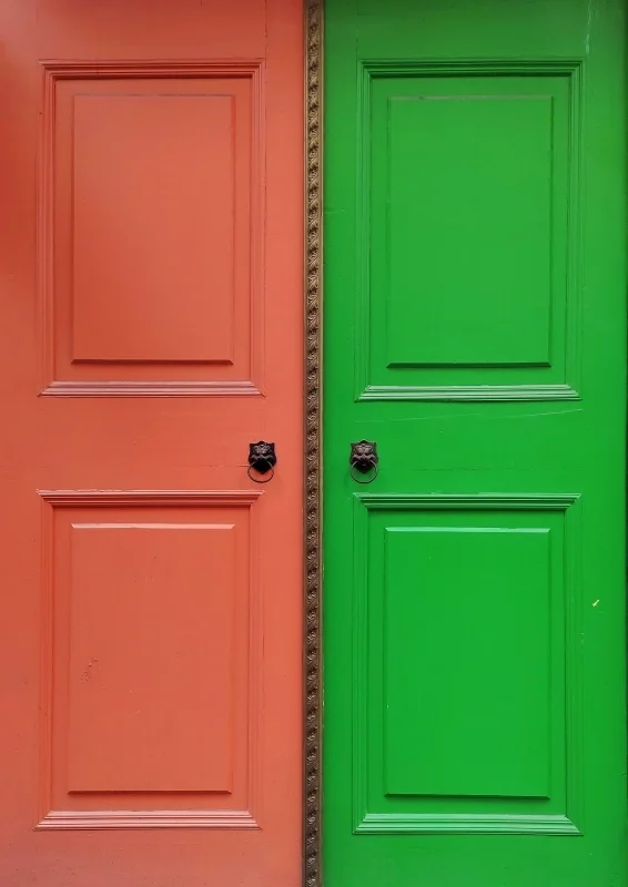 Coral and bright green paneled doors with ornate trim and black door knockers