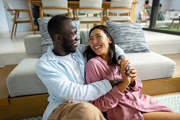Black man and Asian woman embracing and smiling