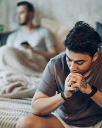 Two men sitting in a bed looking away from each other