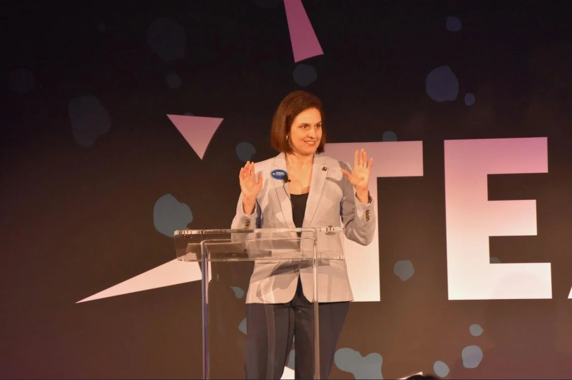 Politician speaking at a podium during a conference or event.