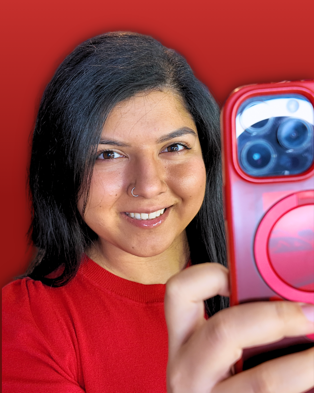 Woman in a red shirt smiling while holding a red smartphone, framed against a red background with blurred social media app icons in the background. Social Media Manager