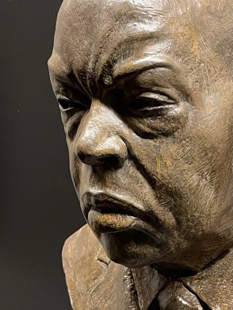 Close-up of a detailed sculpture of a person's face showing an expression of sadness or contemplation.