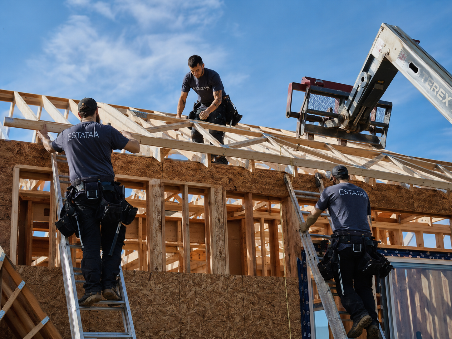 Construction workers installing roof trusses on a building under construction with a clear blue sky in the background.
