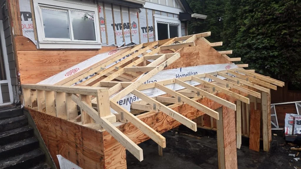 Construction of a new porch or deck attached to a house, with wooden framing and support beams in progress.