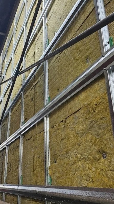 Construction site with metal framing and yellow insulation material on wall