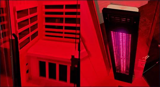 Indoor sauna with red lighting and a heater emitting pinkish-purple light.