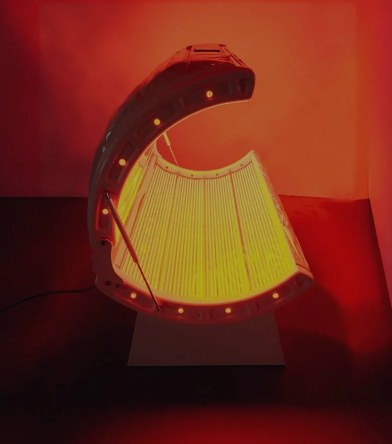 A sunlamp with a curved shape, glowing with red and yellow light, positioned on a white stand in a dark room.