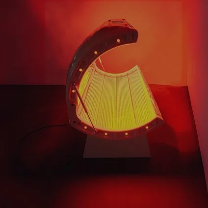 A curved, glowing light fixture with yellowish illumination, set against a red background.