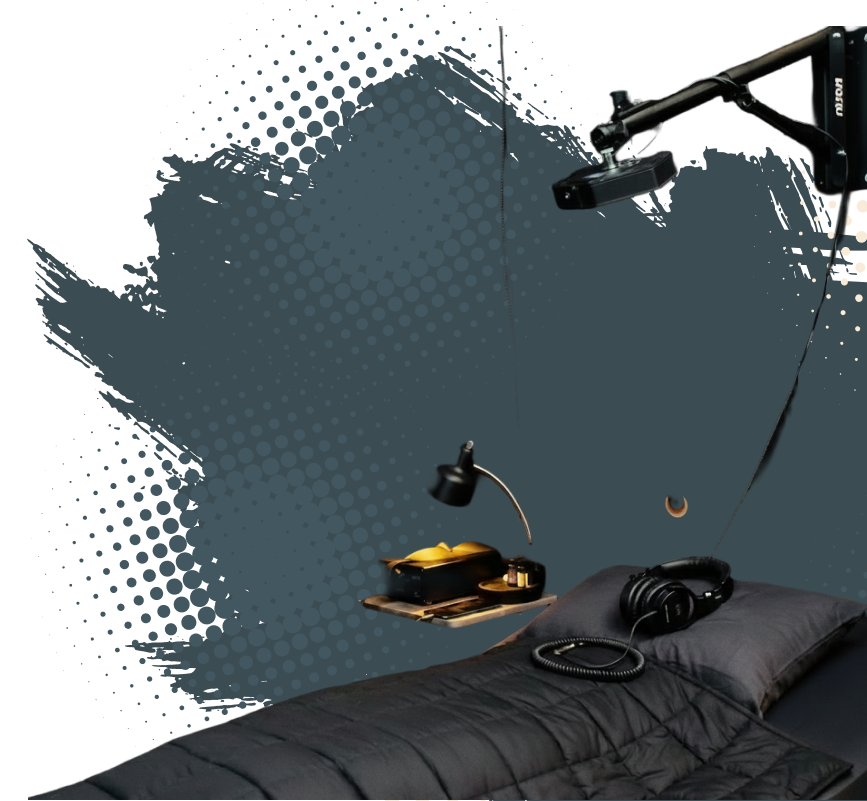 A modern bedroom with a dark blue wall featuring dotted pattern graphics, a black wall-mounted lamp, a black table with a yellow item, and a bed with a black headset on a pillow.
